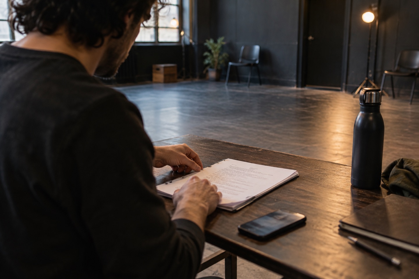 An actor arranging a screenplay and phone before a studio rehearsal